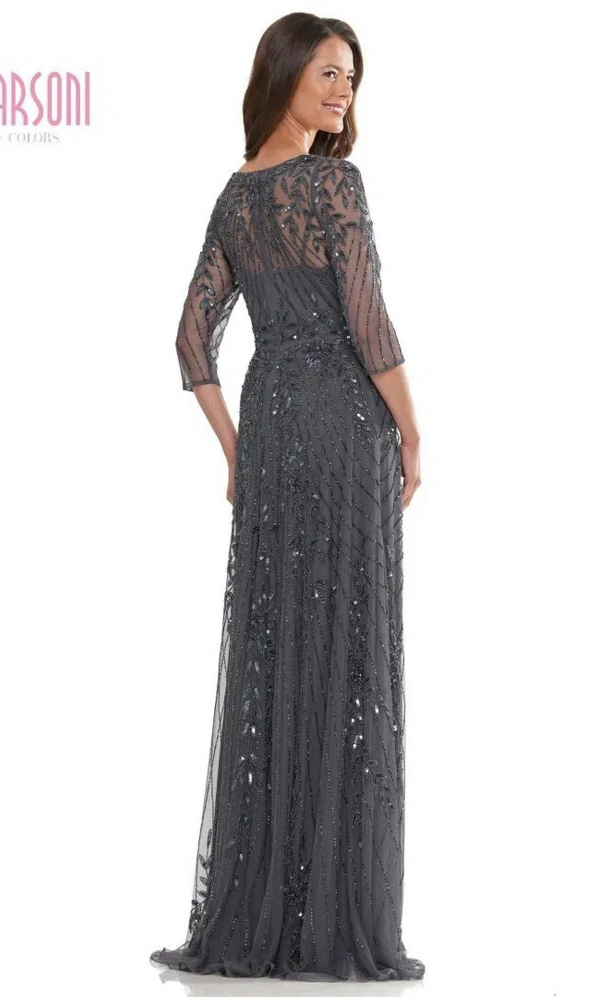Woman facing away and smiling in the Marsoni MV1283 long formal dress, featuring dark sequins, floor-length design, and sheer three-quarter sleeves.
